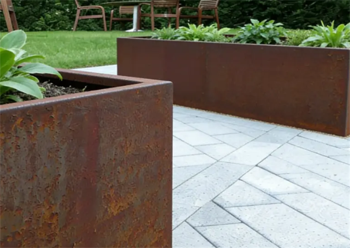 Close-up view of rusted Corten steel trough planters planted with hostas on paved patio