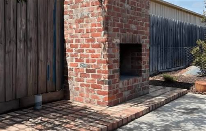 Partially built outdoor fireplace constructed from salvaged reclaimed red bricks